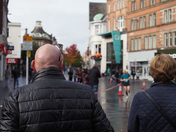 Rear view of couple walking in city during rainy season