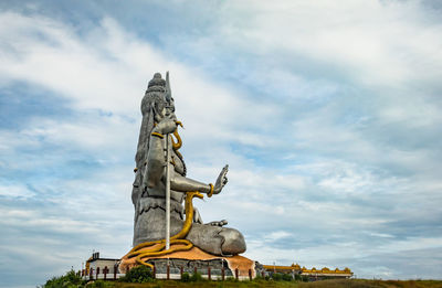 Low angle view of shiva statue against cloudy sky