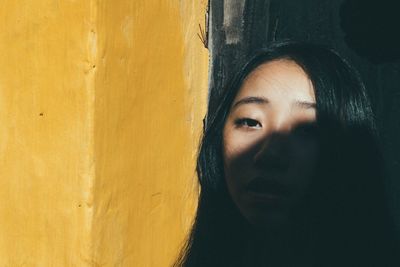 Portrait of young woman by yellow wall