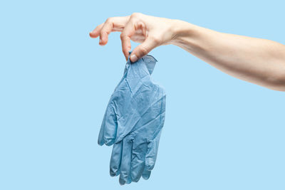 Midsection of person holding umbrella against blue background