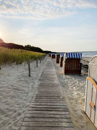 Boardwalk leading towards sea against sky