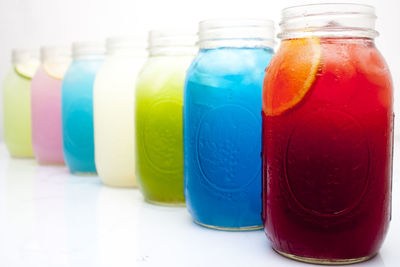 Colorful ice tea in jars on table