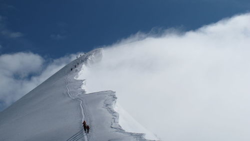 Low angle view of person on snowcapped mountain against sky