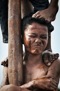 Low section of people standing on boy by pole during panjat pinang