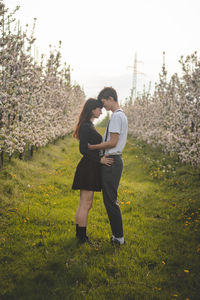 Young strong love between two young people standing under apple trees