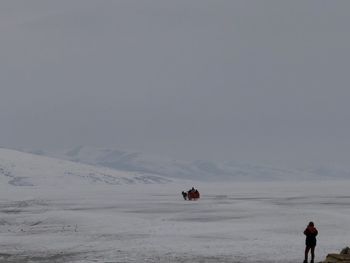 People on snowcapped mountain against sky