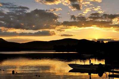 Silhouette boats moored in lake against sky during sunset