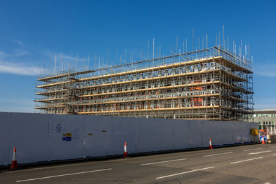 Road by building against blue sky