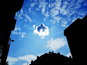 Low angle view of silhouette buildings against blue sky