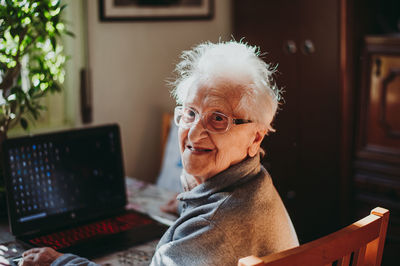 Portrait of smiling senior woman using laptop while sitting at home