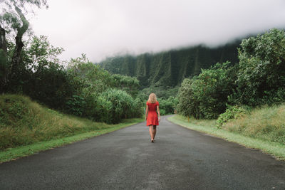 Rear view of woman walking on road against mountains