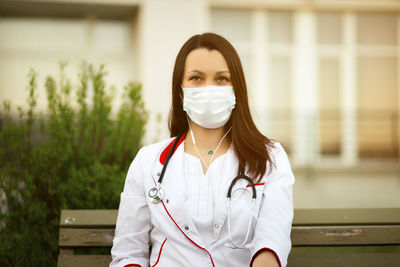 Portrait of doctor wearing mask sitting on bench