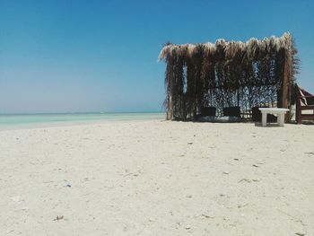 Wooden posts on beach against clear blue sky