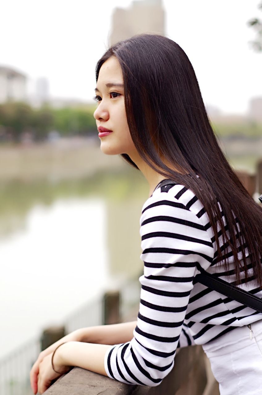 focus on foreground, young adult, lifestyles, young women, casual clothing, long hair, person, leisure activity, waist up, standing, three quarter length, side view, brown hair, medium-length hair, front view, looking away, black hair