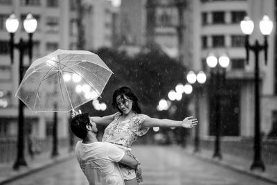 Woman holding umbrella on street in city