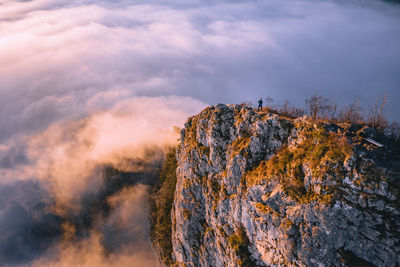 High angle view of man standing on mountain ridge rising above the clouds, hallein, austria