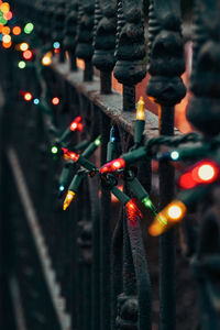 Multicolor christmas lights on vintage iron fence at night diminishing perspective with bokeh