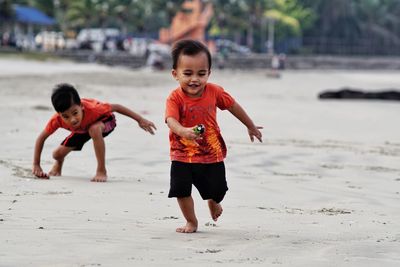 Full length of siblings playing at beach