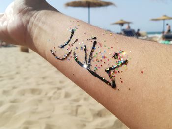 Close-up of hands on sand at beach