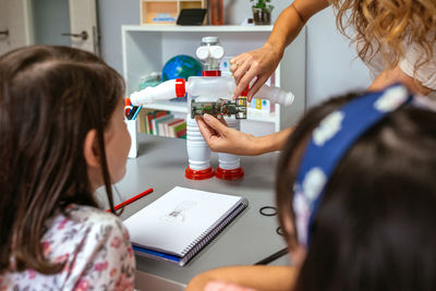 Teacher explaining how to connect electric circuit on recycled toy robot