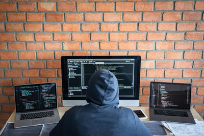 Rear view of man working against brick wall