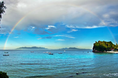 Scenic view of sea against rainbow in sky