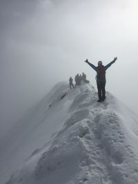 Man standing on snow covered mountain against sky