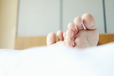 Close-up of human feet on bed at home