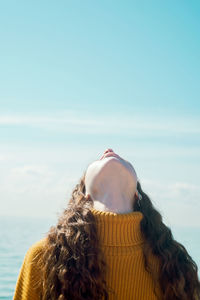 Low angle view of woman looking up while standing against sky