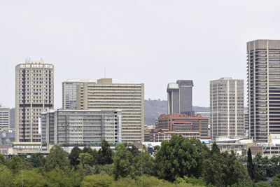 Trees and buildings against clear sky