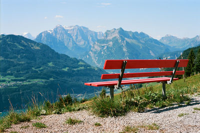 Empty bench in mountains against sky