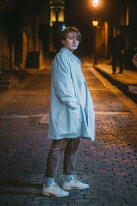 Portrait of boy standing on footpath at night