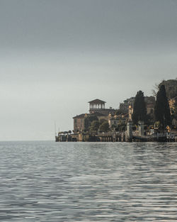 Sea by buildings against clear sky