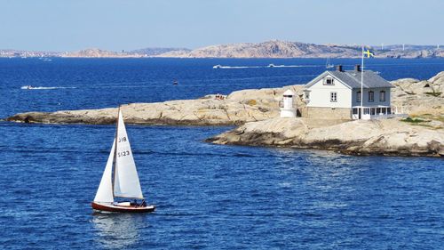 Sailboat on sea by buildings against sky