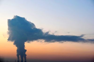 Smoke emitting from chimney against sky at sunset