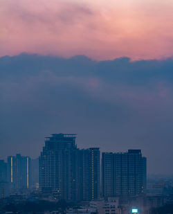 City buildings against cloudy sky at sunrise