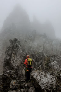 Rear view of man standing on rocky mountain