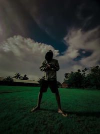 Rear view of man standing on field against sky