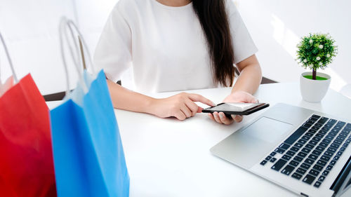 Midsection of woman using laptop on table