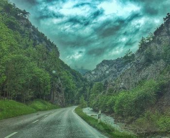 Country road against cloudy sky