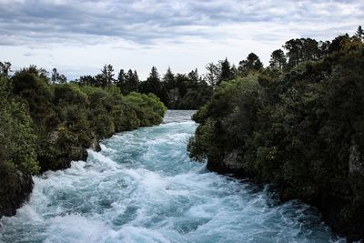 Scenic view of waterfall in forest against sky