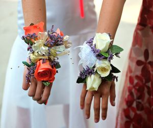 Midsection of women with flowers on hands standing outdoors