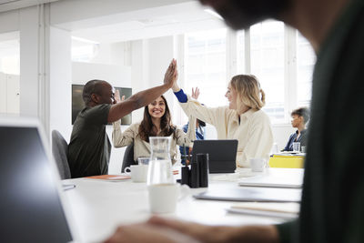 Group of business people high-five during business meeting in office