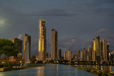 Illuminated modern buildings in city against sky