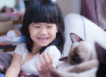 Portrait of cute smiling girl holding cat at home