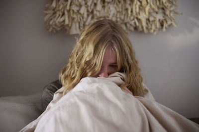 Crying young woman sitting in bed