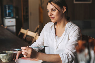 Portrait of a smiling young woman preparing food in restaurant