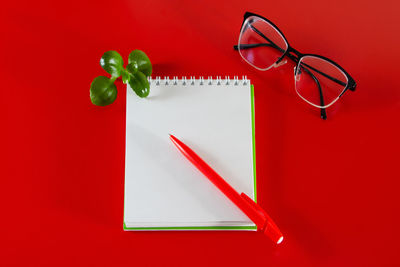 Office supplies on a red background. blank notebook, pen and glasses. layout for design 