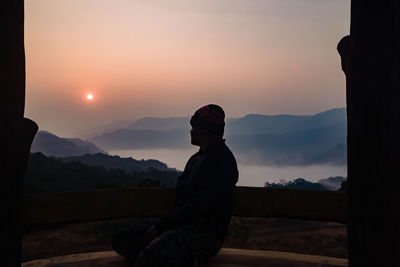 Man standing on mountain against sky during sunset