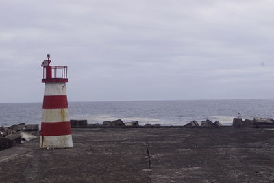 Lighthouse by sea against sky